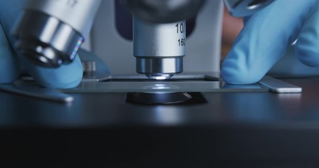 Wall Mural - close-up shot of sample slide and microscope with metal lens at laboratory.