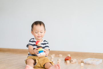 2.5 years baby boy.Little child boy playing stack with colorful wooden toys block alone.Kids play with educational toys at home.Day care and Kindergarten school.child development concept.