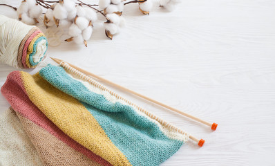 Knitting wool and knitting needles in pastel colors on white background. Cotton bolls. Copy space