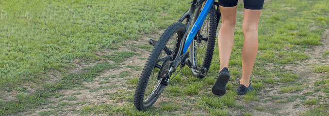 Girl on a mountain bike on road, beautiful portrait of a cyclist at sunset, Fitness girl rides a modern carbon fiber mountain bike in sportswear, a helmet, glasses and gloves.	