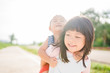 © MIA Studio - Baby boy riding carrying his Big sister on her back.Toddler kid and new sibling.Cute girl and baby boy exercise at the park in Japan.Family with children happy time. Love, trust and tenderness.
