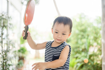 Wall Mural - Asian boy child holding racket and table tennis game outdoor concept.Concentrated little asian toddler boy playing and hitting table tennis ball.