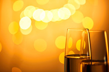 Close Up Of Glasses Of Champagne With Yellow Christmas Lights Bokeh
