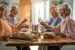 © Drazen - Cheerful senior friends toasting with wine at dining table.