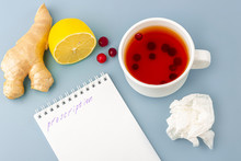 Cup Of Tea With Cranberries, Lemon, Crumpled Napkin, Medical Mask And Prescription On Blue, Copy Space For Text, Close Up. The Concept Of Seasonal Diseases And Treatment Of Colds, Flu, Heat.