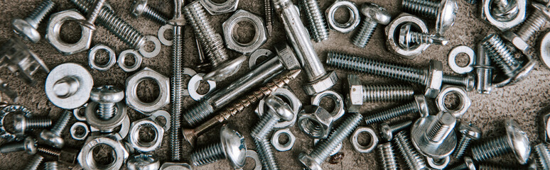 Sticker - top view of metal screws and nails scattered on grey background, panoramic shot