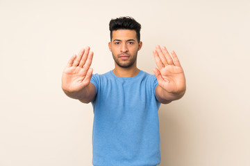 Young handsome man over isolated background making stop gesture and disappointed