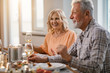 © Drazen - Happy senior woman enjoying in glass of wine during lunch time at home.
