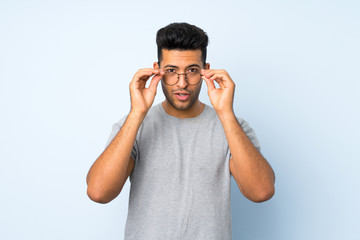 Wall Mural - Young handsome man over isolated background with glasses