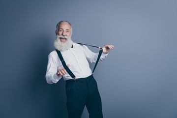 Portrait of his he nice attractive crazy cheerful cheery funny funky gray-haired man pulling suspenders clothes clothing having fun isolated over dark grey pastel color background