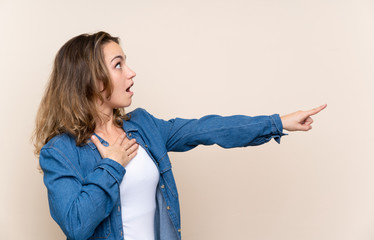 Wall Mural - Young blonde woman over isolated background pointing finger to the side