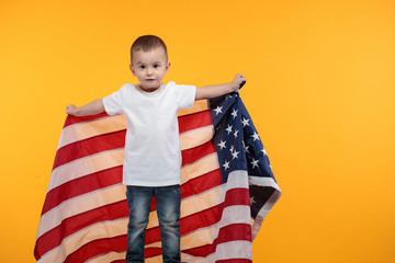 Kid boy wearing white t-shirt with space for your logo or design over yellow background