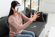 © LIGHTFIELD STUDIOS - emotional woman using Virtual reality headset while sitting on sofa with smartphone