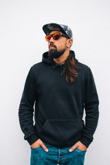 Wall Mural - City portrait of handsome hipster man with beard wearing black blank hoodie or hoody with space for your logo or design. Mockup for print