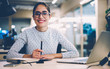 © BullRun - Portrait of cheerful businesswoman satisfied with occupation sitting at desktop in office with modern technologies,smiling female designer happy about accomplished creative project looking at camera