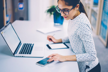 Brunette businesswoman working in office checking notification on smartphone synchronizing netbook files,administrative manager of clinic checking messages on mobile phone making schedule of clients