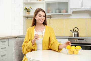 Sticker - Young woman with glass of lemon water in kitchen