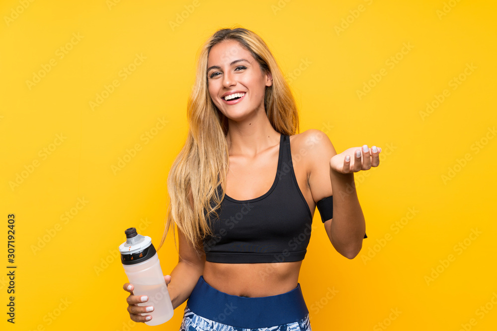 Young sport woman with a bottle of water over isolated background - obrazy, fototapety, plakaty 