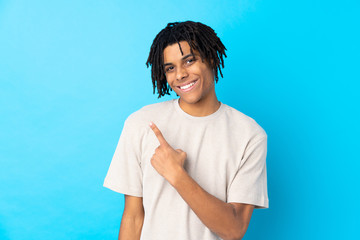 Young African American man over isolated blue background pointing to the side to present a product