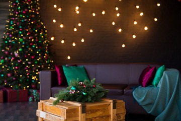 Dark loft interior. Christmas tree with a bunch of boxes with gifts. A beautiful green leather sofa on the background of a gray brick wall with panoramic window.