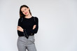 © Вячеслав Чичаев - Concept adult girl on a white background. A photo of a pretty brunette girl in gray trousers and a black sweater smiles and shows different emotions in different poses right in front of the camera.