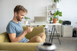 © Westend61 - Smiling man sitting on couch in office using smartphone