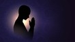 Black silhouette of a praying person, a Buddhist on a background of bright light, a man meditating