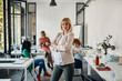 © Westend61 - Portrait of confident pregnant businesswoman in office with colleagues in background