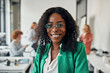 © Westend61 - Portrait of a smiling businesswoman in office with colleagues in background