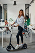 © Westend61 - Portrait of a businesswoman with kick scooter in office