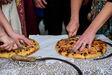 Two women cut home-made bread on the table. Wedding tradition. Turkey. Close up