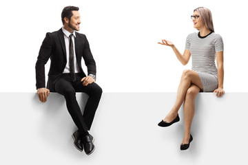 Wall Mural - Young businessman and a young lady having a conversation while sitting on a panel