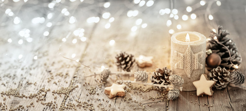 Fototapete - White Christmas candle on rustic wooden boards -  Decoration with natural elements, twigs, pine cones and cookies  -  First Advent Sunday , Advent banner, panorama with magic bokeh lihgts