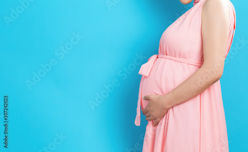 Cuadros en Lienzo Pregnant woman on a solid background holding her belly