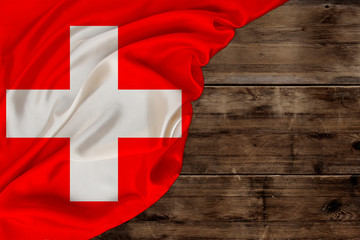 colored national flag of modern state of Switzerland, beautiful silk, old wood background, concept of tourism, economy, politics, emigration, independence day, copy space, template, horizontal