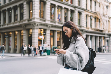 Woman standing on street and messaging on mobile phone