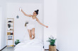 © BullRun - Carefree woman with smartphone in pyjamas dancing on bed