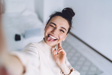 young woman having fun at home using smartphone for selfie