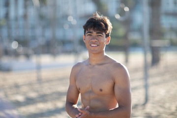 Portrait of a handsome young muscular man in swimwear on the muscle beach at Santa Monica next to fitness equipment