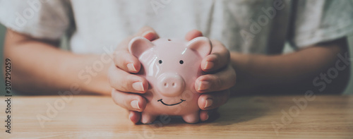 Fotografía Panoramic image, Man hand holding piggy bank on wood table