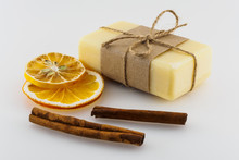 Yellow Handmade Soap, Dry Orange Slices And Cinnamon Sticks On A White Background