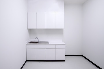 Clean empty white kitchen with sink and cabinet