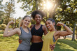 Portrait of an african american female woman standing with her two diverse friends flexing their muscle in the park - 3 woman showing strength and woman power - 3 females flexing biceps 
