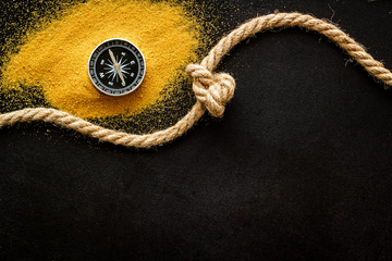 Wall Mural - Goal achievement concept. Compass near rope with knot on black background top view copy space