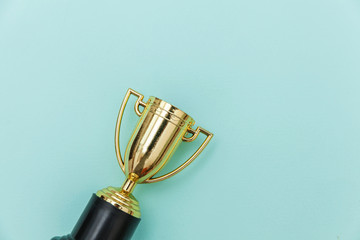 Simply flat lay design winner or champion gold trophy cup isolated on blue pastel colorful background. Victory first place of competition. Winning or success concept. Top view copy space