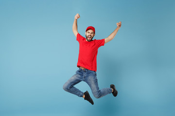 Wall Mural - Delivery man in red uniform workwear isolated on blue wall background, studio portrait. Professional male employee in cap t-shirt print working as courier dealer. Service concept. Mock up copy space.