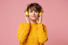 Beautiful Young Brunette Woman Girl In Yellow Sweater Posing Isolated On Pastel Pink Wall Background Studio Portait. People Lifestyle Concept. Mock Up Copy Space. Listening Music With Headphones.