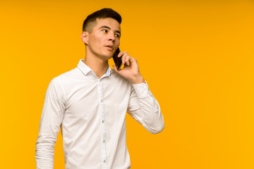 Young male Asian businessman talking seriously on the phone.