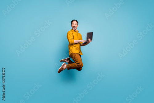 Photographie Full size photo of funky man feel rejoice emotions jump use laptop search social