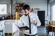 © Dusan Petkovic - Handsome caucasian serious bearded graphic engineer in shirt and tie, holding notebook and looking at it while standing in printing shop.